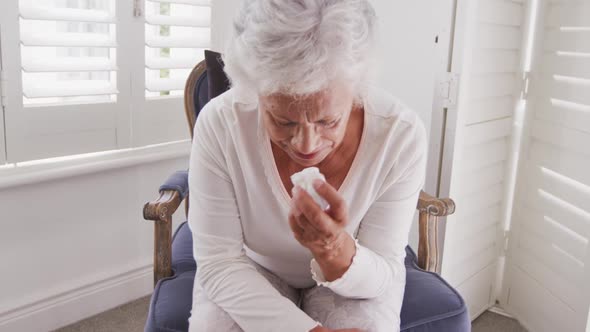 Senior African American woman crying and weeping tears with tissue at home