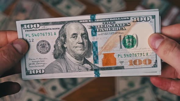 Dollars in Male Hands on Background of Table with Money Counting Banknotes