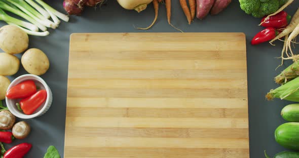 Video of fresh fruit and vegetables and wooden chopping board with copy space on grey background