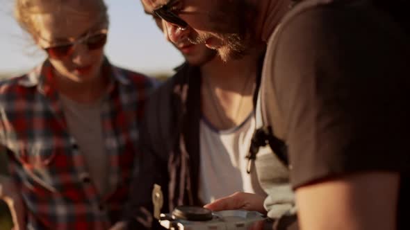 Bearded Spectacled Caucasian Male Holding Map and Compass Surrounded By Two Friends Trying to Find