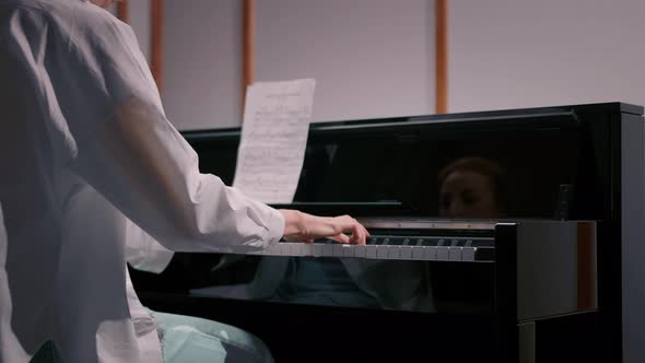 Woman sensually playing the piano view from the back