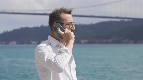 Businessman talking on the phone by the sea.