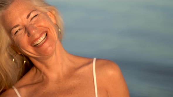 Extreme closeup of mature woman laughing out loud and looking at camera.