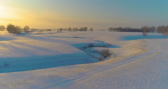 Aerial View of Cold Arctic Field Landscape Trees with Frost Snow Ice River and Sun Rays Over Horizon