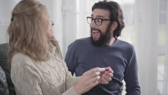 Adult Caucasian Man in Eyeglasses Looking at Affirmative Pregnancy Test, Smiling and Hugging