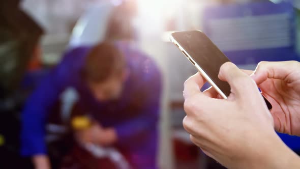 Hands of woman using mobile phone while mechanic showing thumbs up