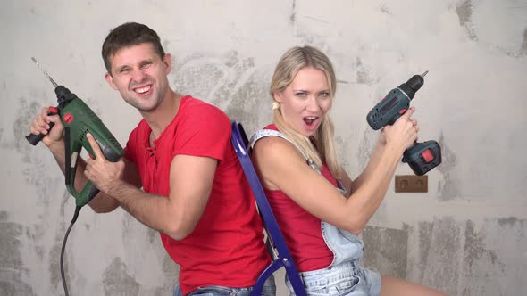 Positive Young Married Couple with Tools on the Background of Home Renovation