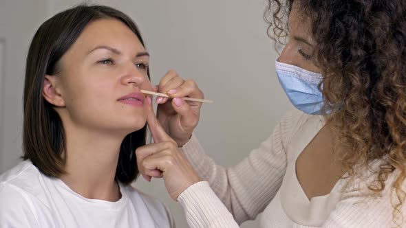 Professional Cosmetologist Performs Wax Epilation on the Patient's Upper Lip