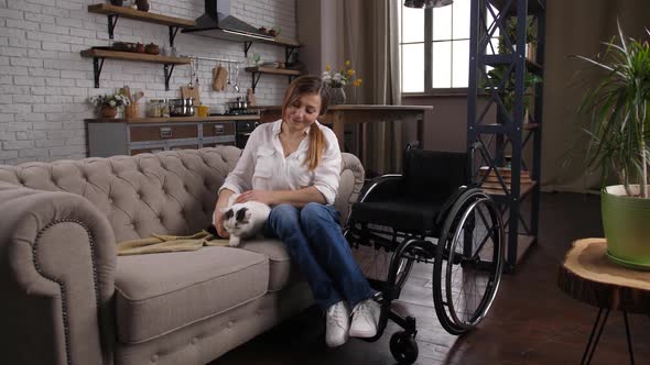 Positive Handicapped Female Caressing Cat on Couch