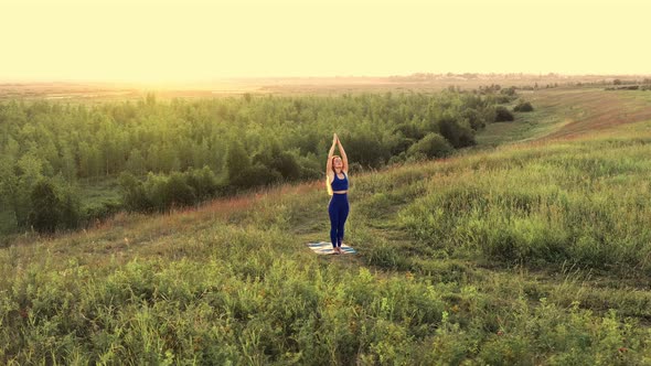 Woman Is Doing Yoga. Dawn, Green Field.