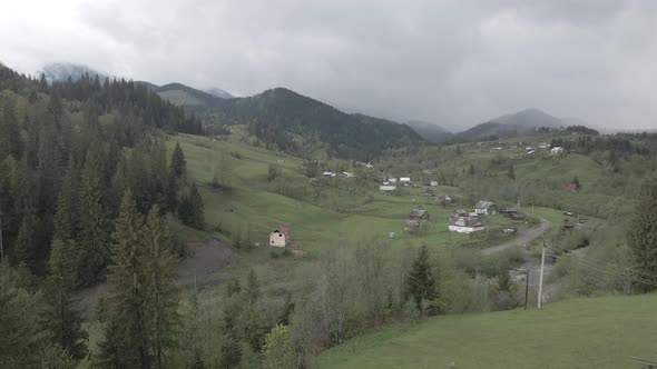 Village in the Mountains. Slow Motion. Carpathians. Ukraine. Aerial. Gray, Flat