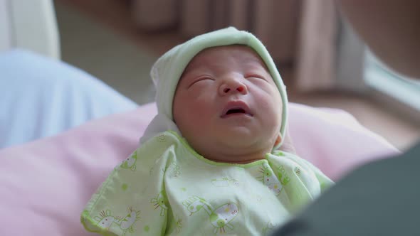 asian mother looking newborn baby boy sleeping in hand at hospital