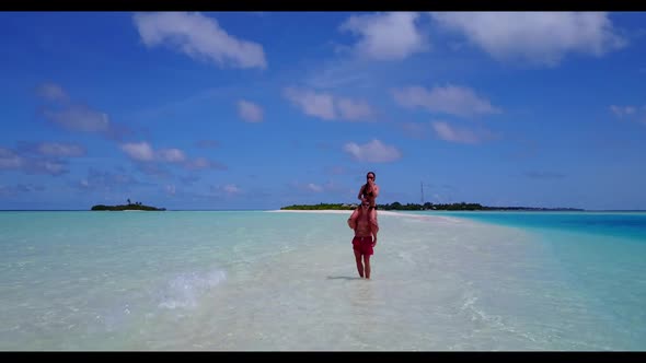 Family of two in love on perfect lagoon beach vacation by blue green ocean with white sand backgroun