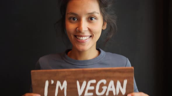 Young Mixed Race Woman Holding Wooden I Am Vegan Sign