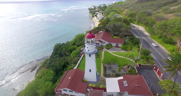 Circling aerial shot of a lighthouse on a cliff near the ocean in Hawaii