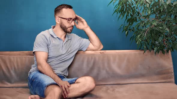 Domestic Male Sit on Couch Feeling Tiredness Massaging Temples