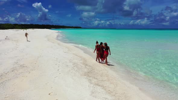 Women enjoying life on idyllic tourist beach time by shallow ocean with white sandy background of th