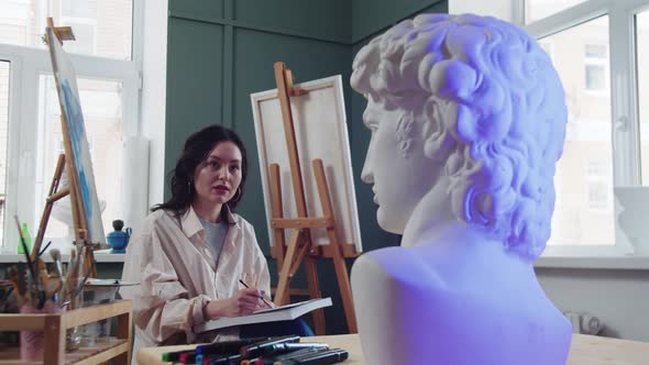 A Woman Artist Sketches From the Marble Bust in an Art Studio