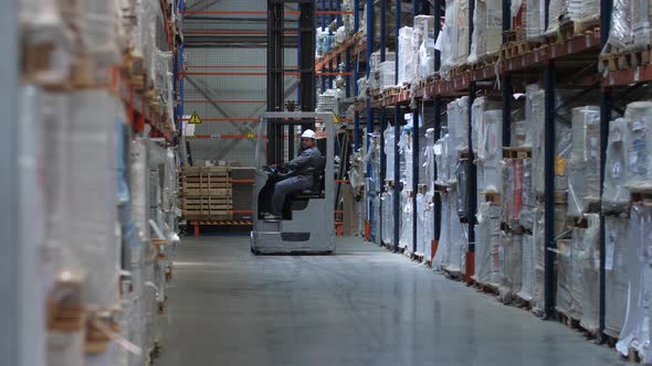 A Forklift Drives Along Huge Stands with Goods in a Logistic Warehouse