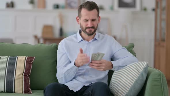 Tense Young Man Counting Dollar at Home