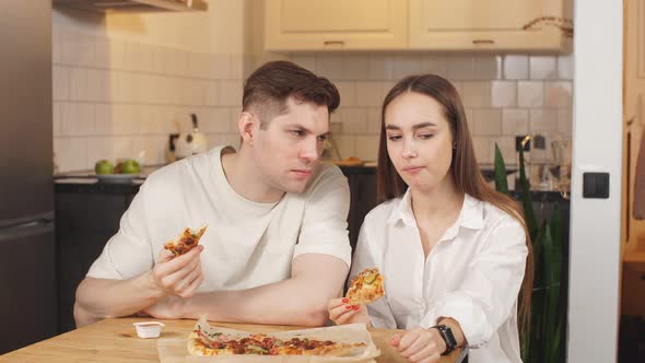 Young Couple with Discontent Eats Pizza at Home