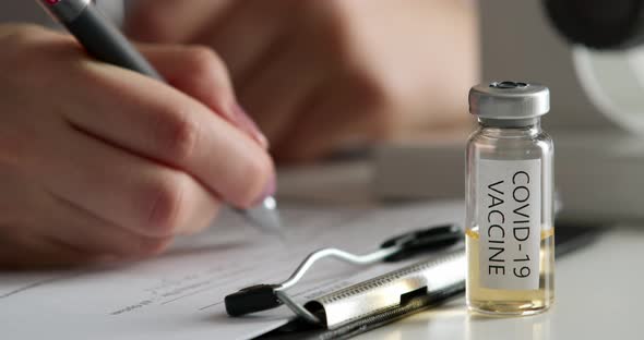 COVID-19 Vaccine. Close-up Shooting. The Lab Worker Is Filling Out the Documents. Experiments in the