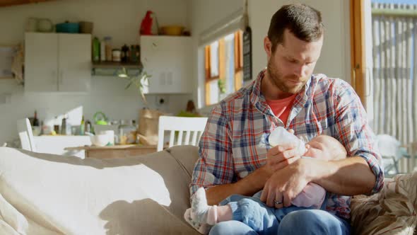 Front view of mid adult caucasian father feeding milk his baby from bottle in a comfortable home 4k