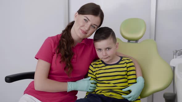 Portrait of Happy Female Dentist with a Child Smiling at Camera in Dental Chair