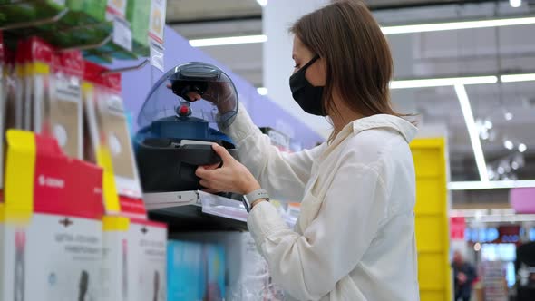 Woman Choosing a Vacuum Cleaner in the Store