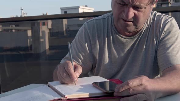 Senior Man Calculating Money On The Terrace Of The House