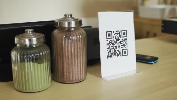 Spices in jars, plaque with qr code and smartphone lying on countertop