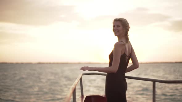 Happy Slim Girl in Black Dress Looking at Sunset During Ferry Trip Across Sea
