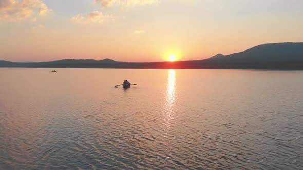 People Sailing on the Boats with Paddles on the River on the Late Sunset