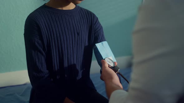 Doctor Checking Arterial Pressure Using Tonometer on African Girl Arm Close Up