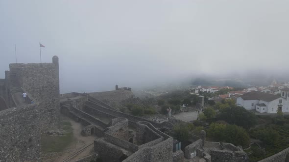 A drone flies through the mist over an ancient castle.