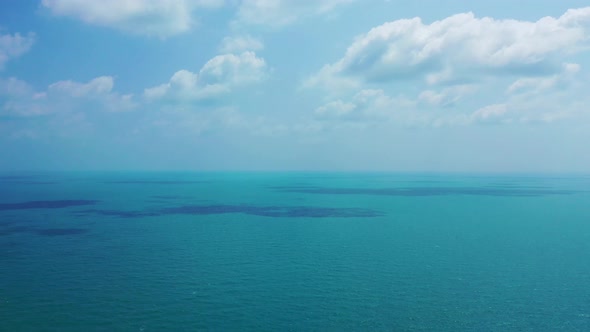 Misty sky with clouds rising over ocean horizon shining turquoise sea surface near shoreline of trop