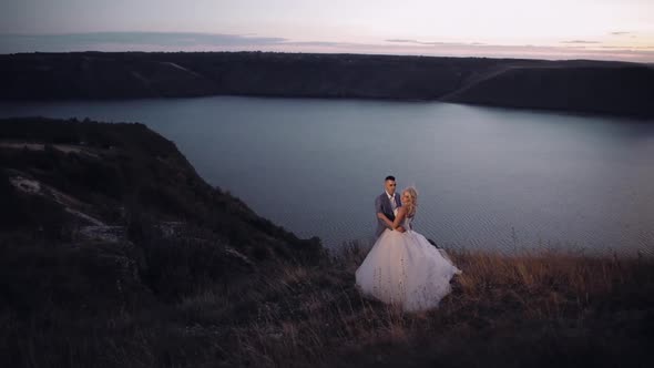 Newlyweds Couple on a Mountain Near River. Sunset. Groom and Bride