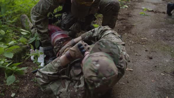 Combat Medic Taking First Aid Kit Applying Bandage to Wounded Leg
