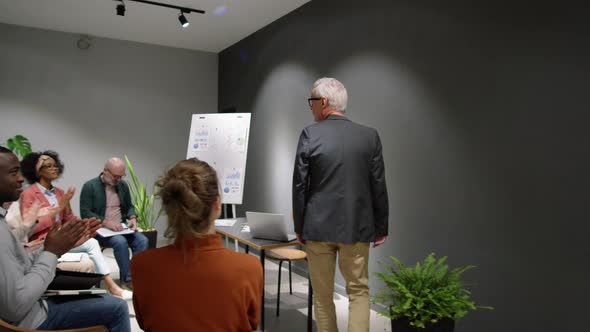 Senior Business Coach Entering Seminar Room and Greeting Audience