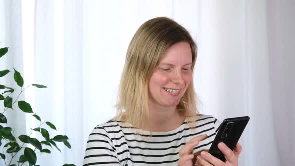 Young Smiling Caucasian Woman with Dental Braces in Striped Tshirt Making Video Call Mobile Phone