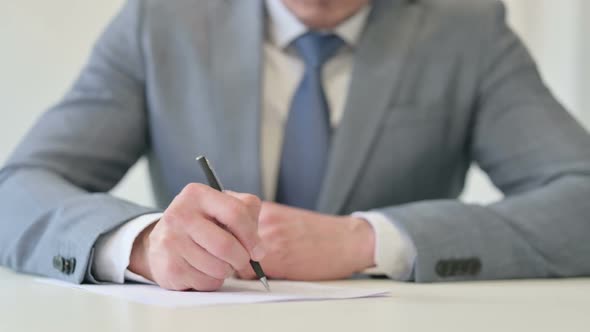 Close Up of Businessman Writing on Paper with Pen