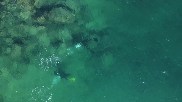 Unique view of scuba divers below the water exploring a man-made artificial reef with bubbles breaki