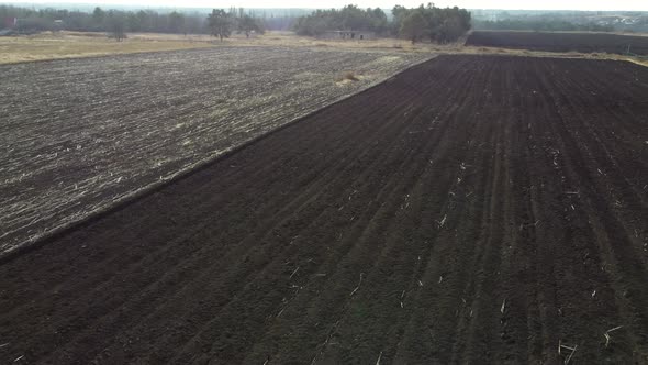 Aerial Drone View Flight Over Field of Plowed Brown Earth