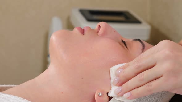 Beauty Clinic. Beautician Cleans Female Face Preparing for Subsequent Beauty Procedures in Salon