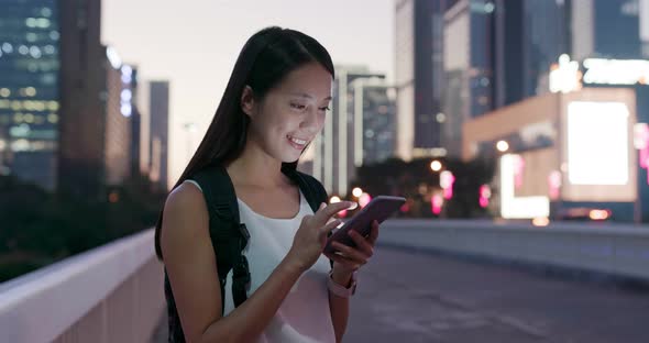 Woman work on mobile phone in city at evening time