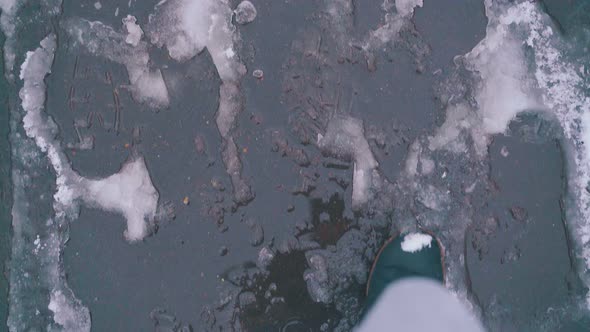 Hurrying Man in Boots Walks Fast Along Street with Slush