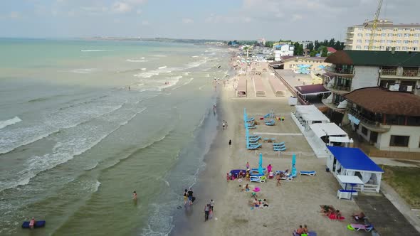 Aerial view of beach with tourists, sunbeds and umbrellas at a luxury hotel.