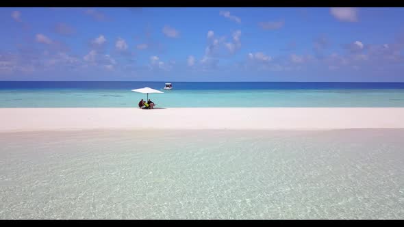 Family of two tan on tropical shore beach trip by blue water and bright sand background of the Maldi