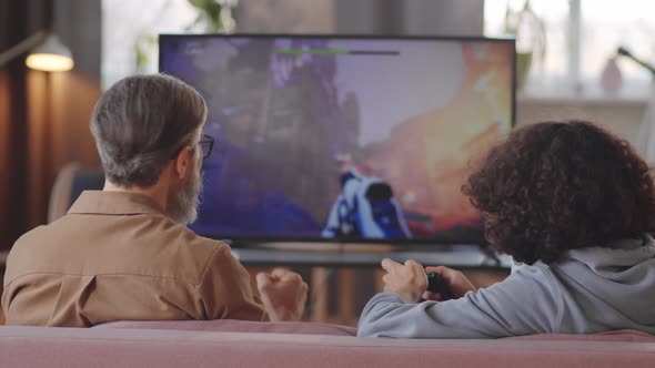 Father and Son Playing Shooter Game on TV