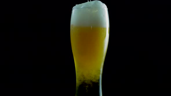 Light Beer In A Beer Glass,Pouring Fresh Draft Beer Into A Glass On A Black Background